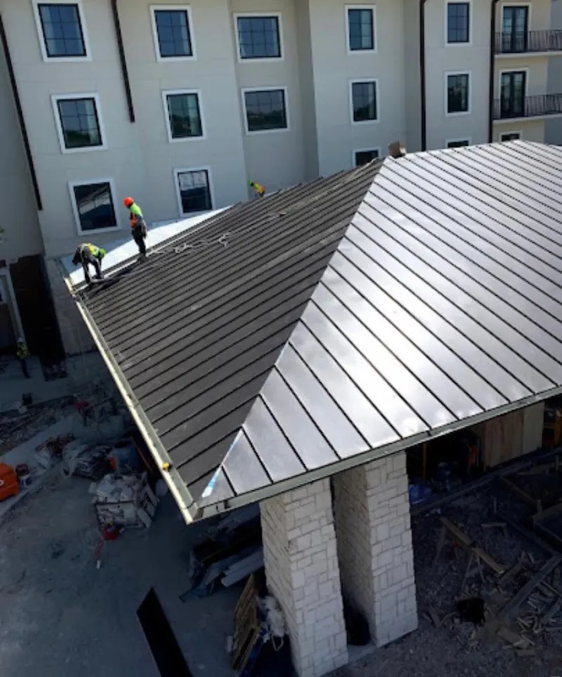Crew installing standing seam metal roof panels on a commercial project in DuBois